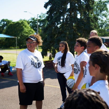 coach speaking with young athletes at a Lansing basketball camp